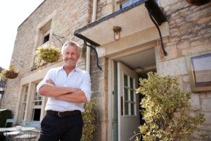 Senior male restaurant pub owner stands outside the entrance